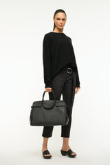 Maude carryall bag in black worn over shoulder with silver ring hardware.