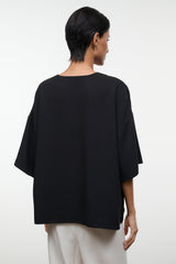 Back view of black studio tee with short sleeves and relaxed, boxy fit