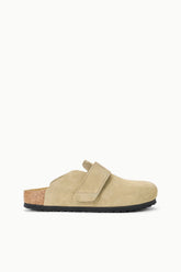 A single beige suede clog shoe with a hook-and-loop strap closure, a cork-look midsole, and a black outsole, shown in profile against a solid white background.