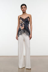 Noir floral silk camisole top with lace hem and adjustable straps, worn with white trousers