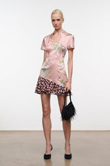 Pink silk dress with short sleeves, floral print, and black polka-dot ruffle hem