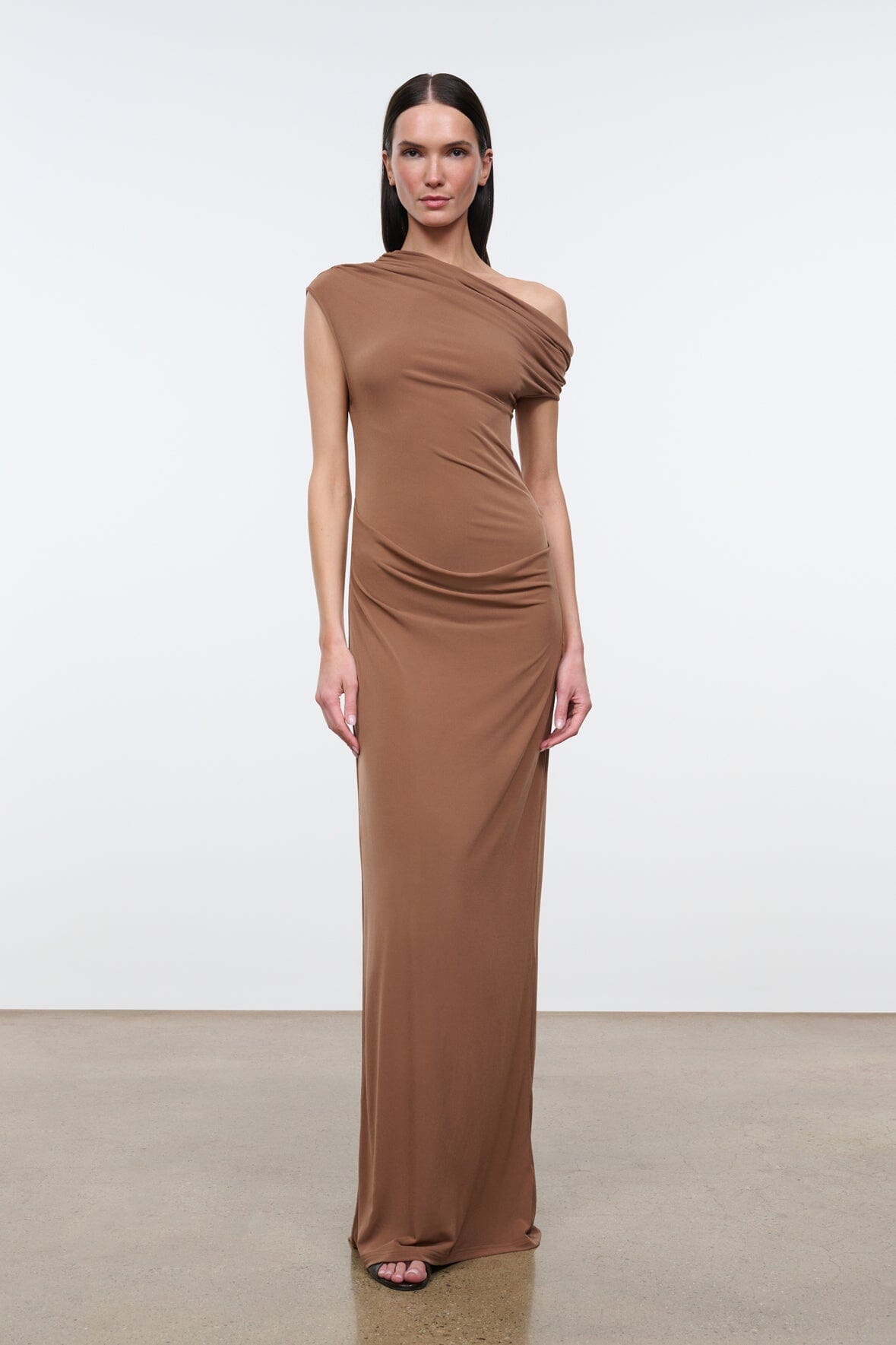 Women's draped one-shoulder maxi dress in warm brown, sleeveless with ruched waist.