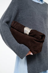 Espresso suede cuff clutch with silver-tone clasp, held in hand
