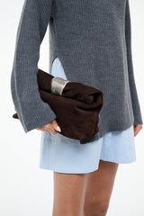 Suede cuff clutch with silver-tone cuff detail, held at side