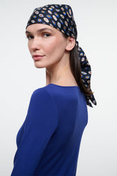 Silk scarf headwrap in dark navy with multicolor circle pattern, tied at side