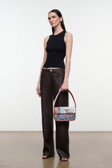 Beaded mini bag with red handles and multicolor pattern, worn by model