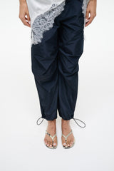 Snake-print thong sandals worn with navy drawstring pants and lace trim