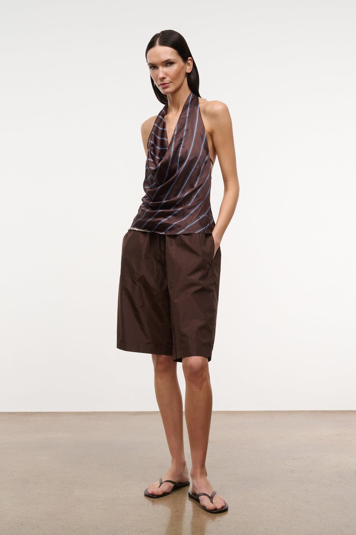 Earth-colored bermuda shorts, knee-length, with front pleats and side pockets