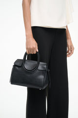 Black Maude mini carryall bag held by model, structured mini shape with top handle