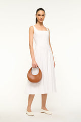 Mini moon bag tan leather worn crossbody with curved top and short strap.
