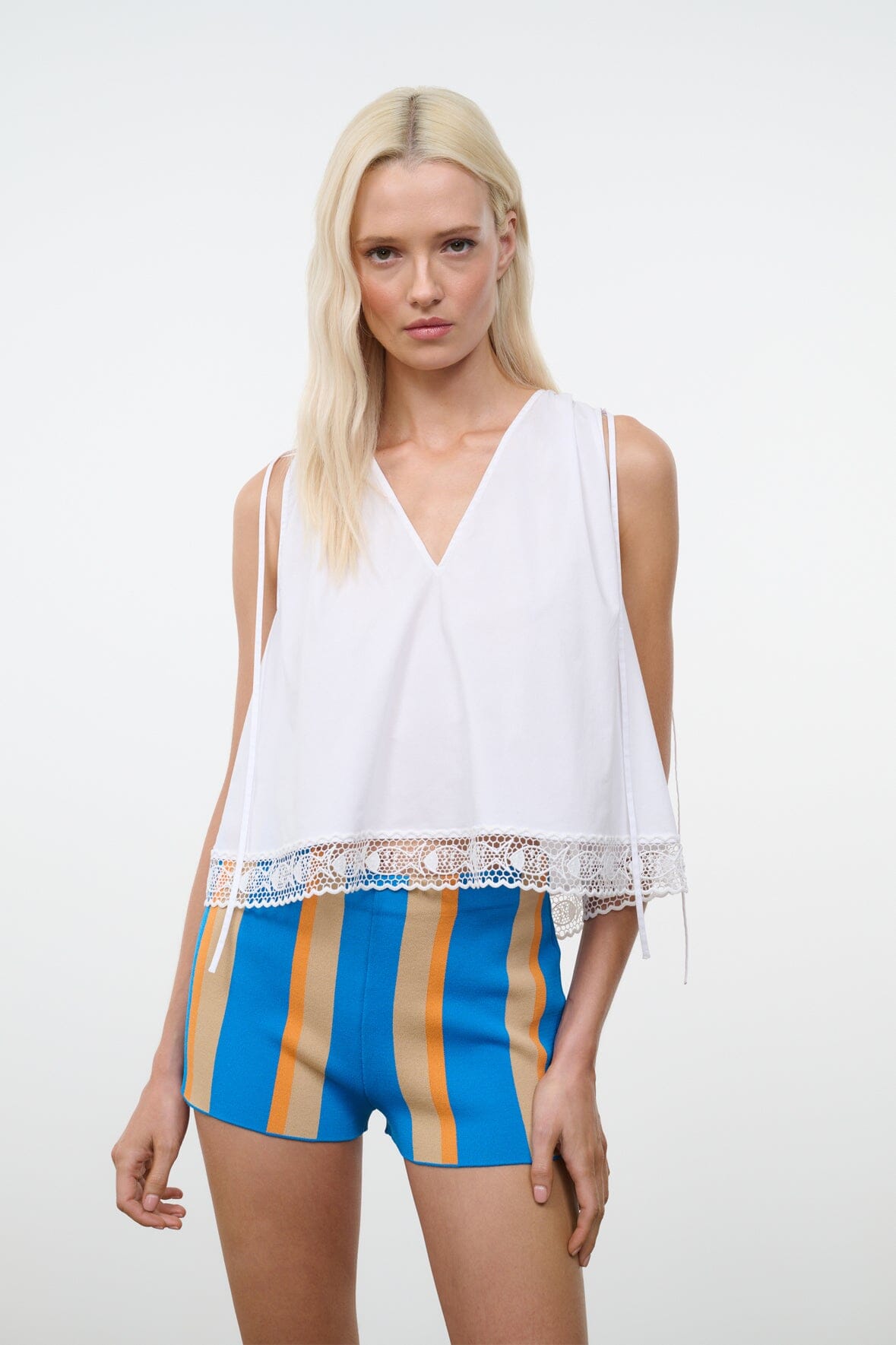 White sleeveless V-neck top with lace panel hem and loose fit