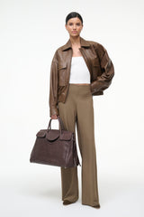 Large Maude carryall bag in espresso brown, held by model with front flap detail