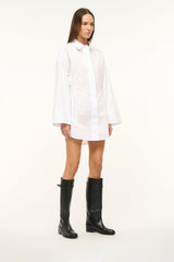 Black riding boots worn with short white shirt dress
