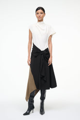 Sleeveless high-neck dress with white upper and black knotted waist, asymmetrical tan panel