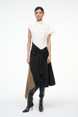 Sleeveless high-neck dress with white upper and black knotted waist, asymmetrical tan panel