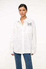 White oversized button-up shirt with cat graphic patch on chest pocket