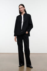 Black shirt jacket with stand collar and button front, long sleeves; front three-quarter view.