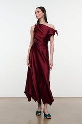 Deep burgundy silk midi dress with one-shoulder drape and flowing asymmetrical hem