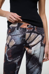 Flare jeans detail: abstract butterfly print with orange and gray swirls, dark base