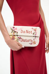 Close-up of cream tweed bag with red “Do Not Disturb” embroidery