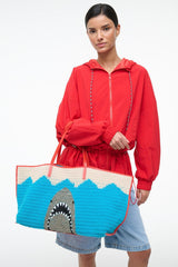 Large tote bag with blue knit body, cream stripe, red handles, shark graphic front panel