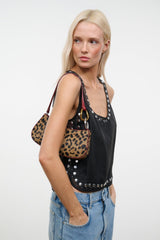 Cheetah-print bag on shoulder with burgundy trim and gold rings