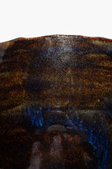 Close-up of textured dark ceramic candle rim and wax edge
