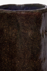 Close-up of dark speckled ceramic candle side with glazed textured speckle