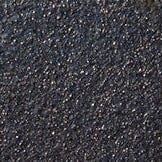 Dark burnt black ceramic glaze texture with speckled finish on a round surface