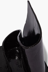 Black glazed wavy holder close-up, curved teardrop opening with glossy finish