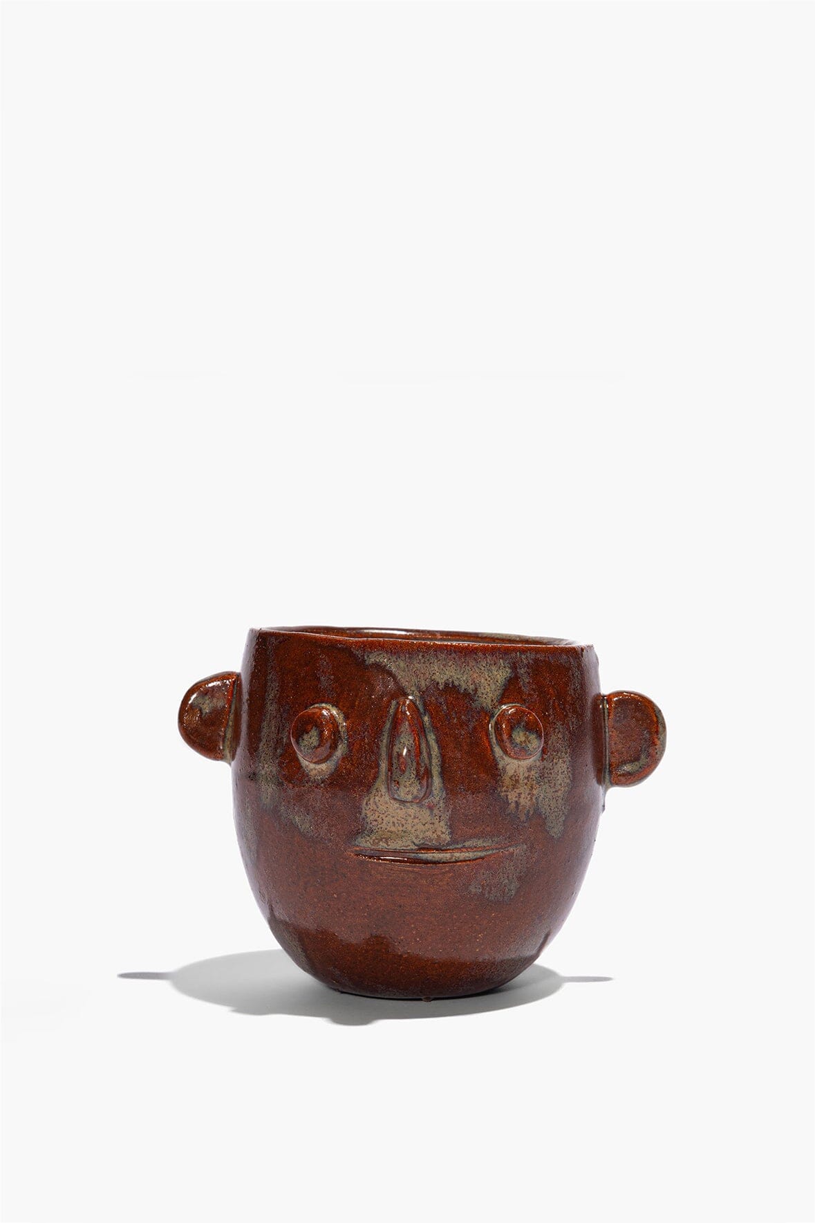 Ceramic candle pot with brown glaze, side handles, and raised face features; open top