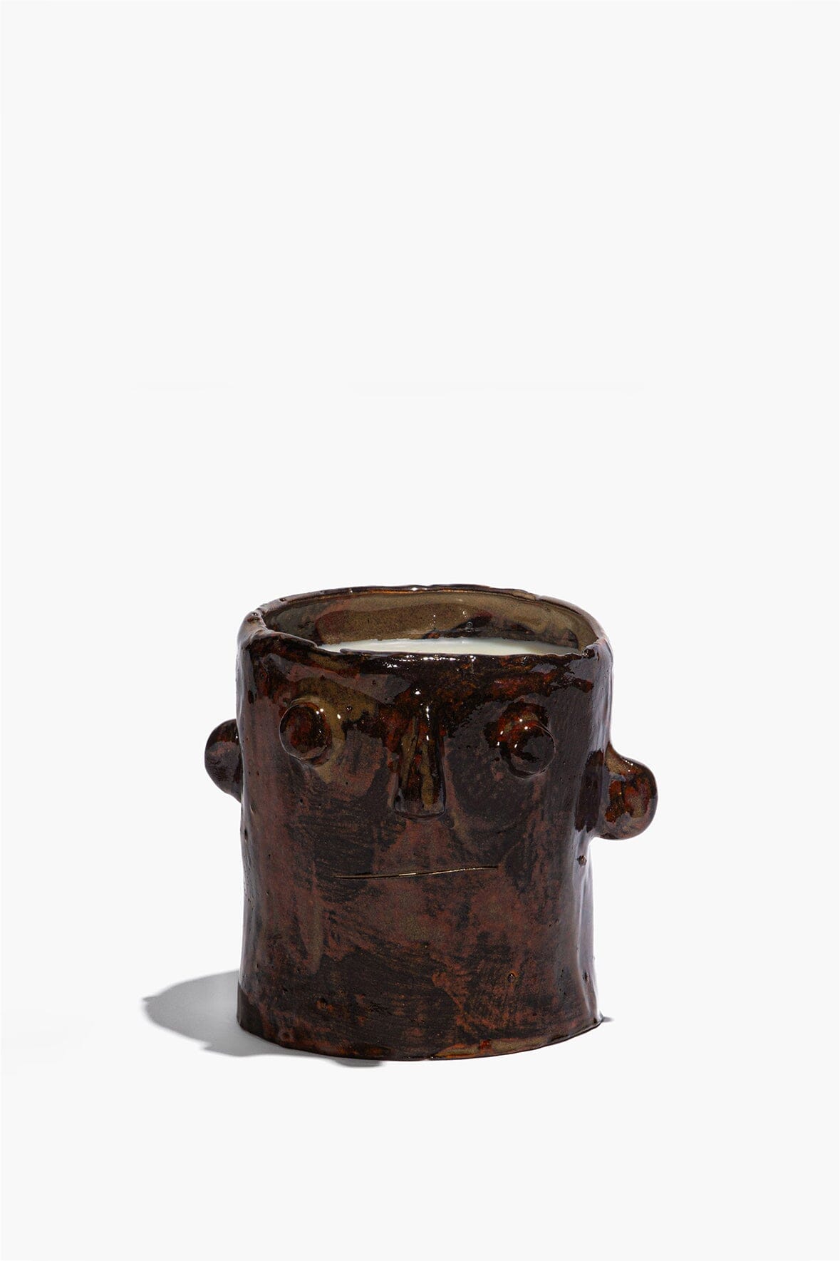 Brown ceramic candle holder with sculpted face, circular side details, open top