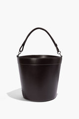 Dark brown leather bin with arched carry handles, stitched rim and smooth bucket silhouette.