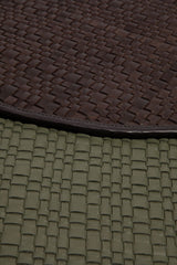 Moss green leather placemat edge with woven pattern and dark brown trim, close-up