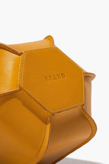 Goldenrod leather bottle vase detail with embossed logo on front panel