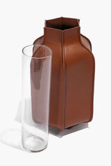 Tan leather bottle vase next to clear glass cylinder for display