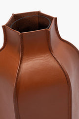 Tan leather bottle vase with open top and seam stitching around the neck
