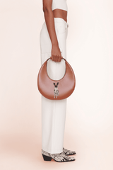 Tan crescent moon bag with front pet-face emblem and rounded top handle