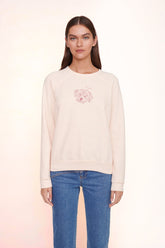 Light pink sweatshirt with small rose-like chest graphic, ribbed cuffs and hem