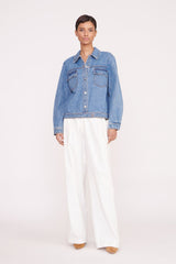 Medium-wash denim jacket on model with button front, flap chest pockets, long sleeves
