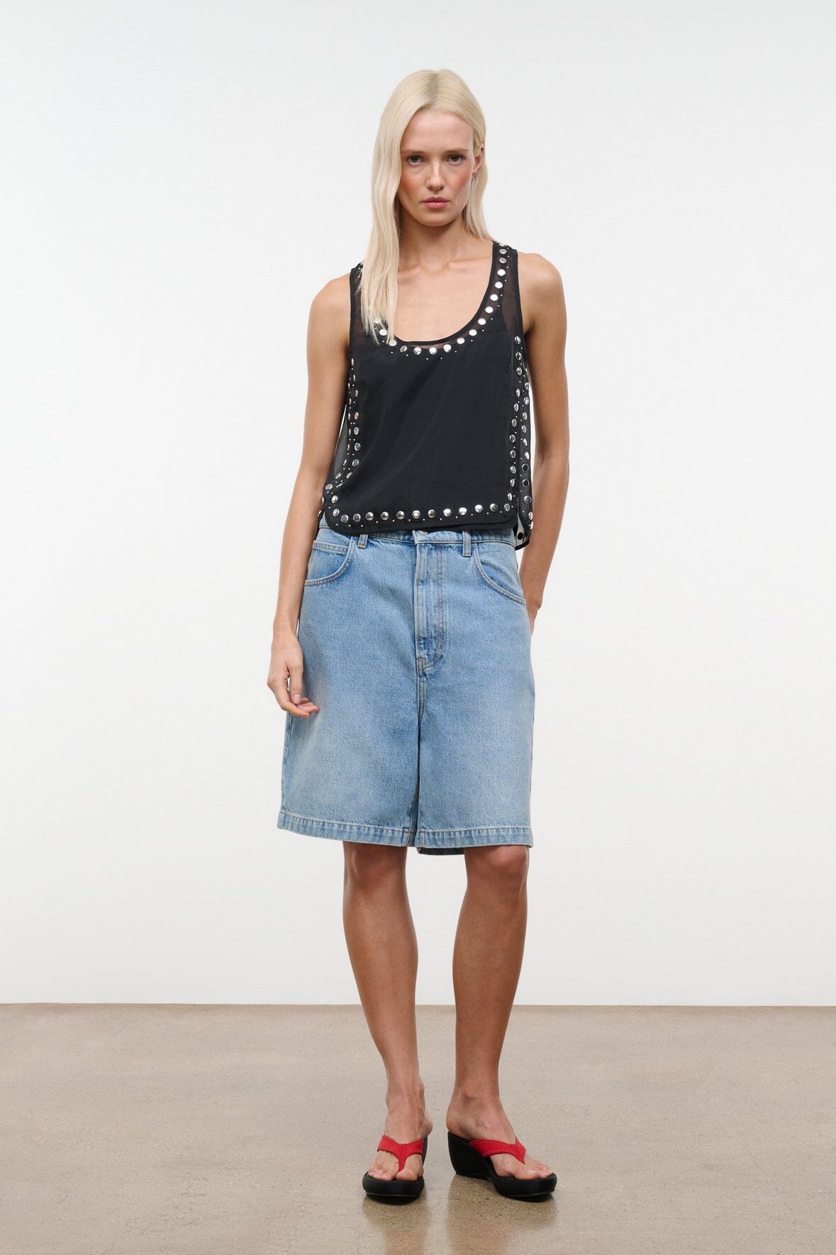 Black studded tank top with scoop neckline and silver stud border, standing front view