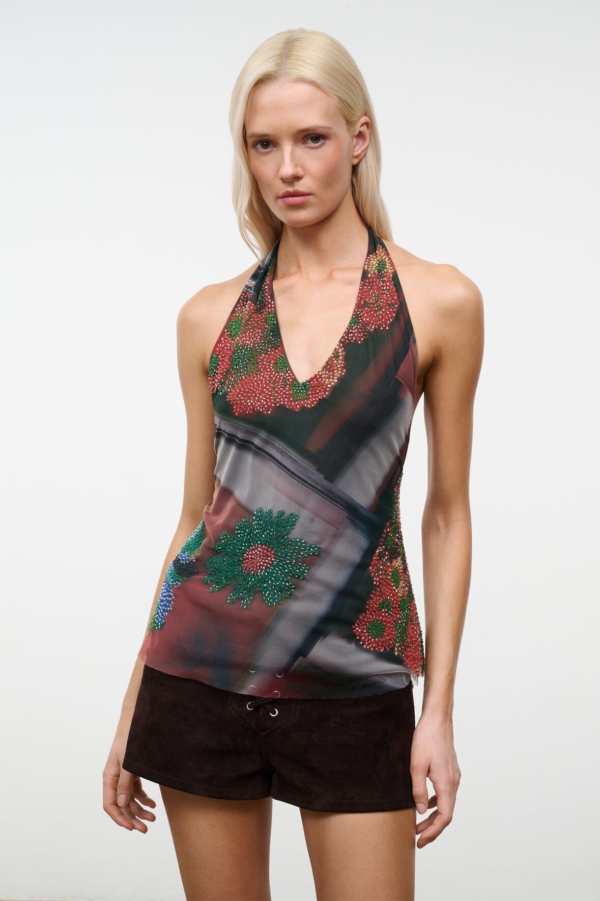 Close-up sleeveless beaded V-neck top with dark floral pattern and sheer beaded details