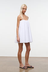White mini babydoll dress with spaghetti straps, lace trim, and flared skirt.