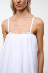 White mini dress bodice close-up with lace trim and thin spaghetti straps.