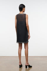 Black sleeveless mini dress, back view, with stud-trim hem and side accents
