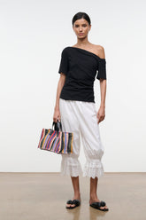 Black Carine top with diagonal off-shoulder neckline and short sleeves, side front view