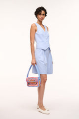 Model holding a light blue beaded mini bag with colorful embroidered front