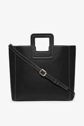 Black leather tote bag with adjustable crossbody strap and metal buckle