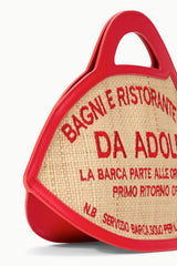 Fish-shaped tote bag close-up: beige weave with red border and DA ADOLFO text