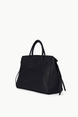 Maude carryall bag in black with structured top handles and dangling tassel straps.